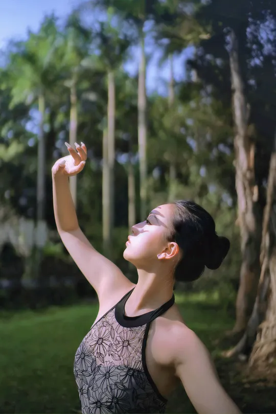 一个年轻女子在公园里 双手举过头顶 张开双臂。