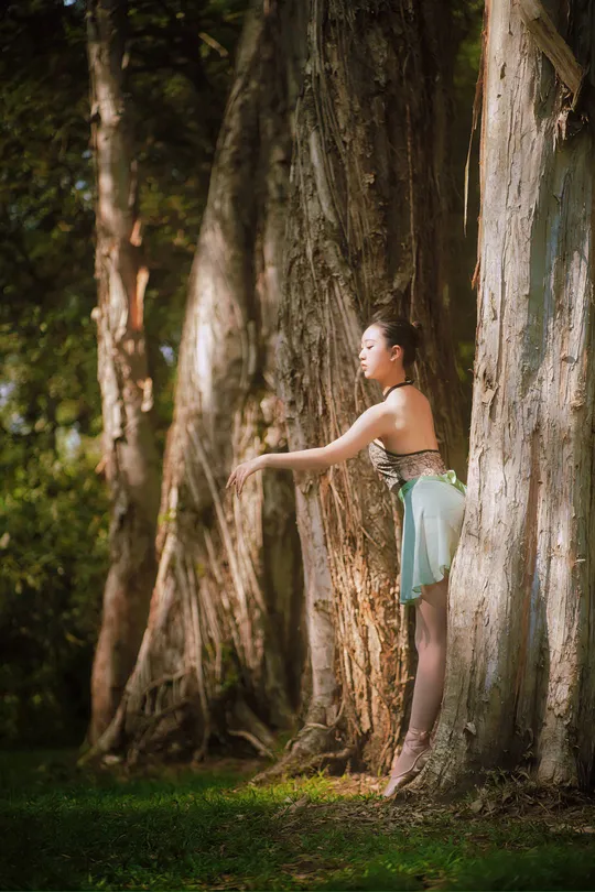站在森林中的一棵树旁的年轻女子
