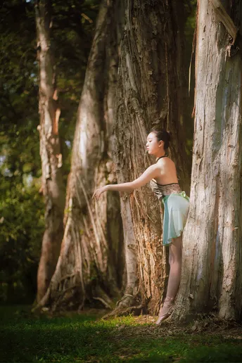 站在森林中的一棵树旁的年轻女子