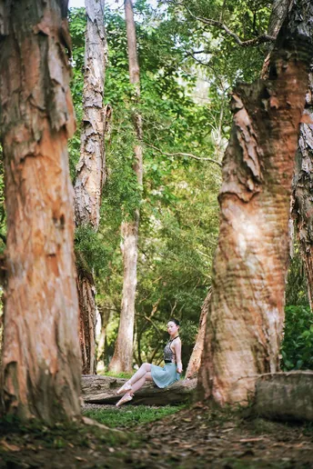 一位年轻女子在森林中坐在树上练习瑜伽
