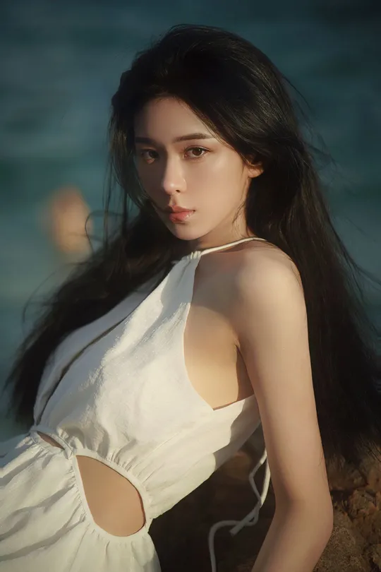 一位长发年轻女子穿着白色长裙在海滩上