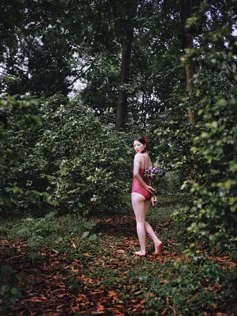 一位年轻女子穿过森林 树木和花丛。