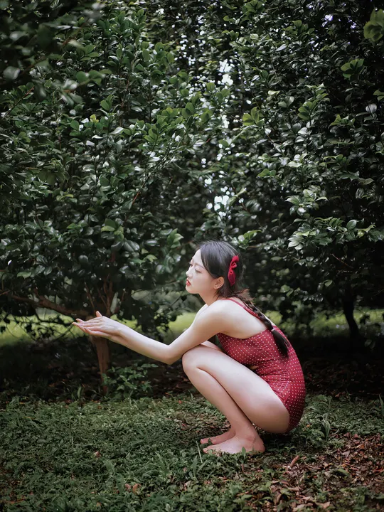 一位穿着红裙子的年轻女子从苹果树上摘苹果