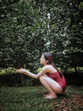 一位穿着红裙子的年轻女子从苹果树上摘苹果