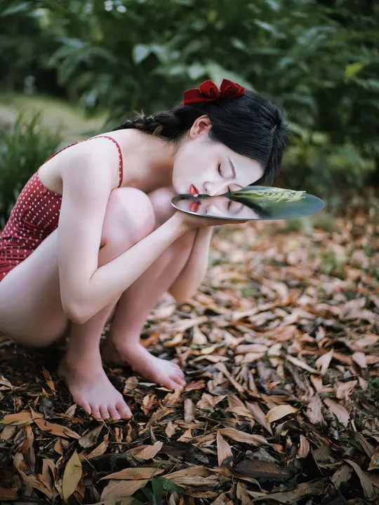 一位穿着连衣裙的年轻女子手里拿着一片叶子