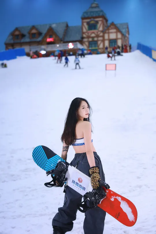 一位年轻女子站在雪地中 携带一个单板滑雪板。