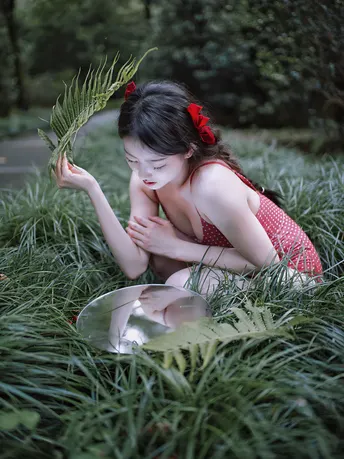 一位年轻女子坐在草地上 手里拿着一株植物。