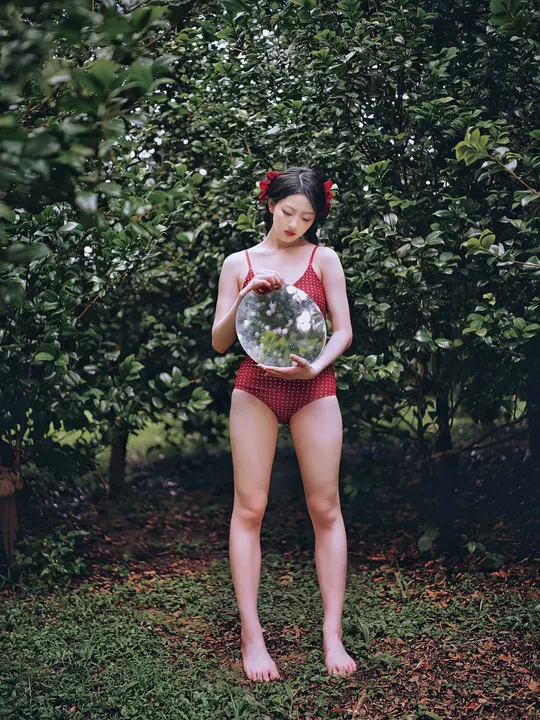 站在树前的年轻女子手持球