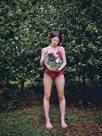 站在树前的年轻女子手持球