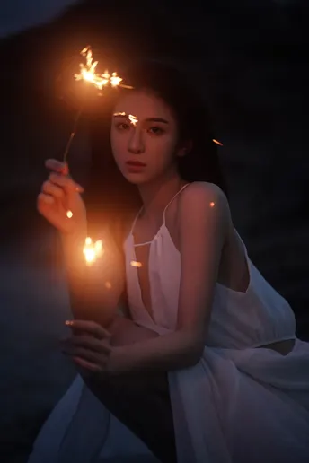 一个穿着白色连衣裙的年轻女子手里拿着一支点燃的蜡烛