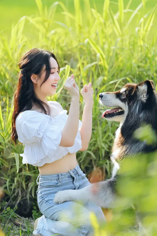 一位年轻女子在草地上与她的狗玩耍