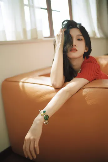 一个穿着红裙子的年轻女子坐在橙色沙发上