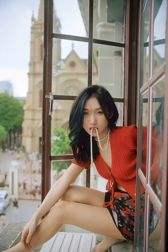 一位穿着红裙子的女人坐在窗户上摆姿势