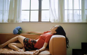 一个年轻女子躺在带有窗户和一张沙发床的房间里 沙发床上躺着一个女孩。