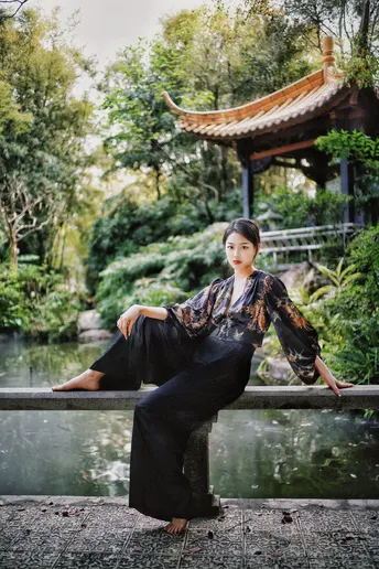 一位穿着黑色和服的美女在池塘边摆姿势