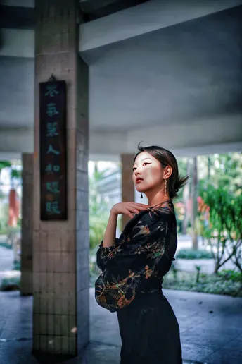 一个穿着黑色连衣裙的年轻女子站在一把伞下