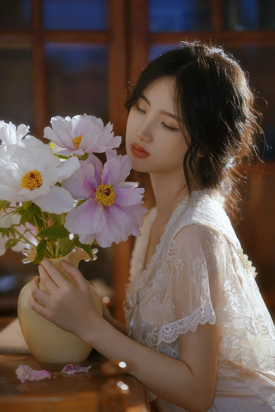 一位年轻女子手持一束白花花束 放在花瓶中。