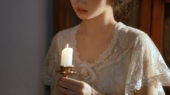 一位穿着白色连衣裙的女人拿着点燃的蜡烛的肖像