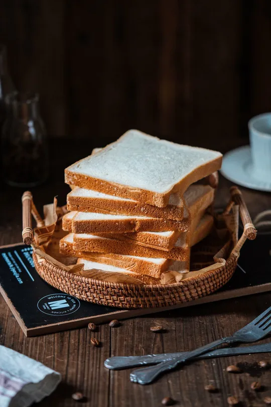 一个木制桌子 上面放着一盘面包和一杯咖啡。