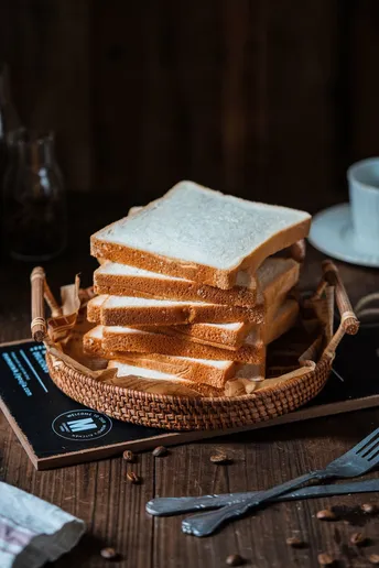 一个木制桌子 上面放着一盘面包和一杯咖啡。