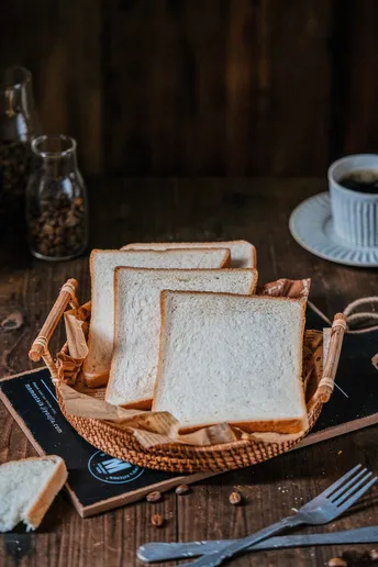 一个木制桌子 上面放着一盘面包和一杯咖啡。
