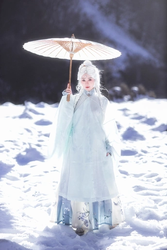 一位穿着白色连衣裙 手持雨伞在雪中的女人