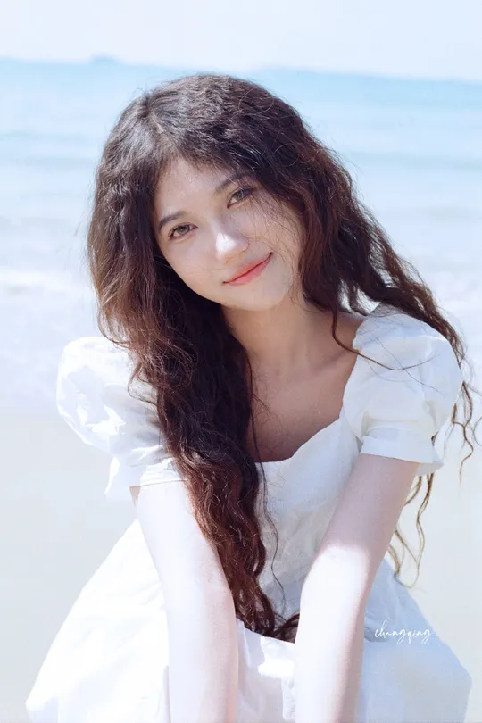 一位美丽的年轻女子穿着白色连衣裙在海滩上的肖像