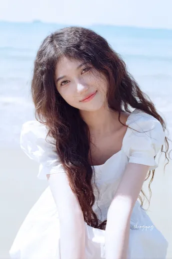 一位美丽的年轻女子穿着白色连衣裙在海滩上的肖像