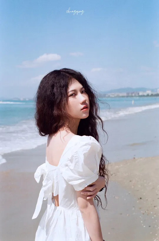 一位穿着白色连衣裙站在海边的女人