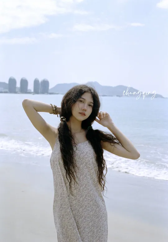 一位长发女子穿着裙子在海滩上摆姿势