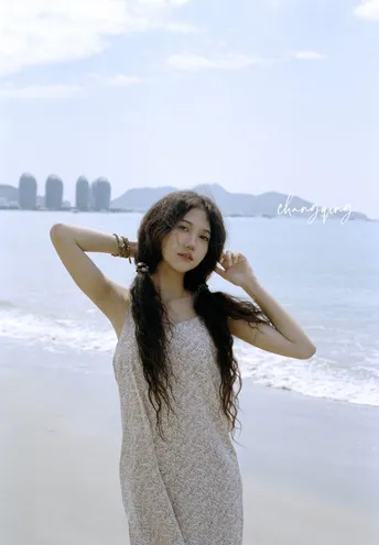 一位长发女子穿着裙子在海滩上摆姿势