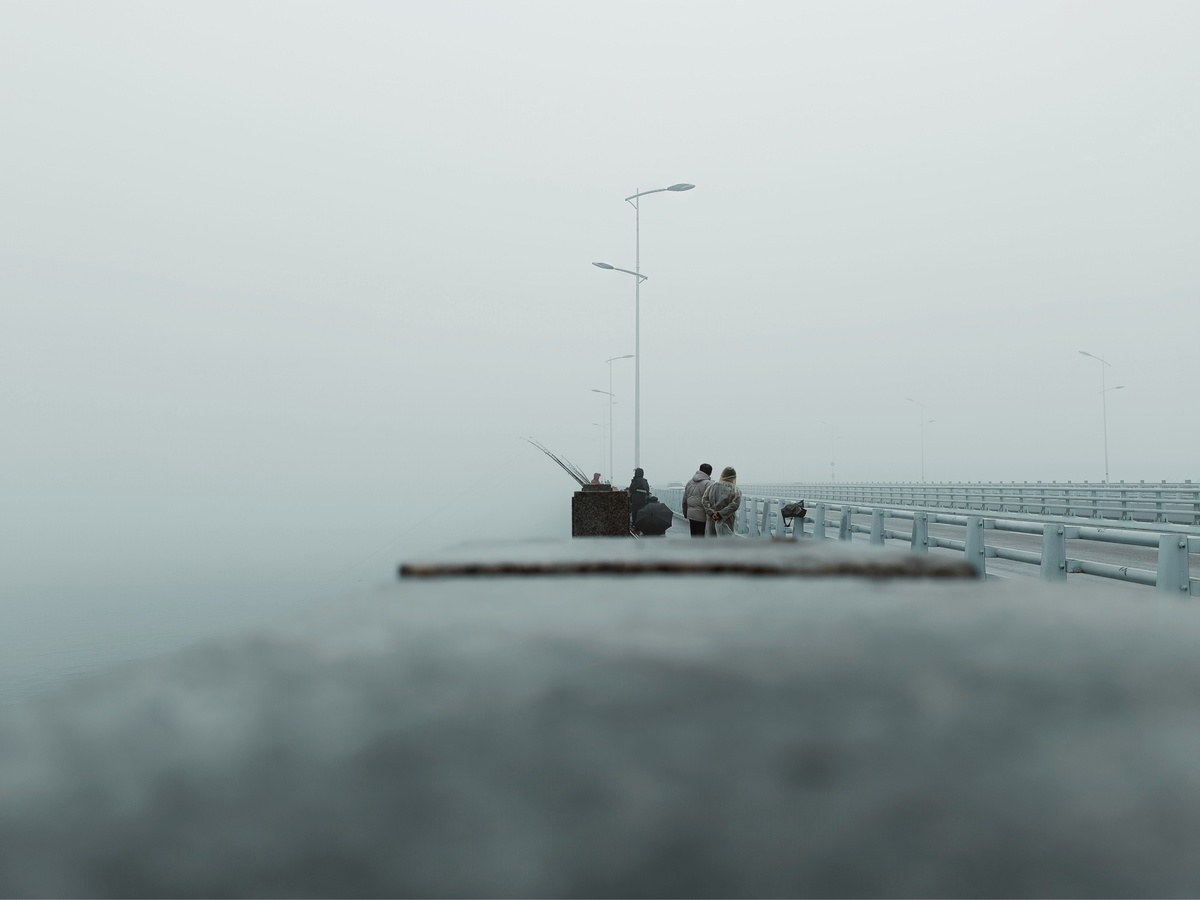 雾中 pier 上的船和水中的一个人在桥上雾中坐着