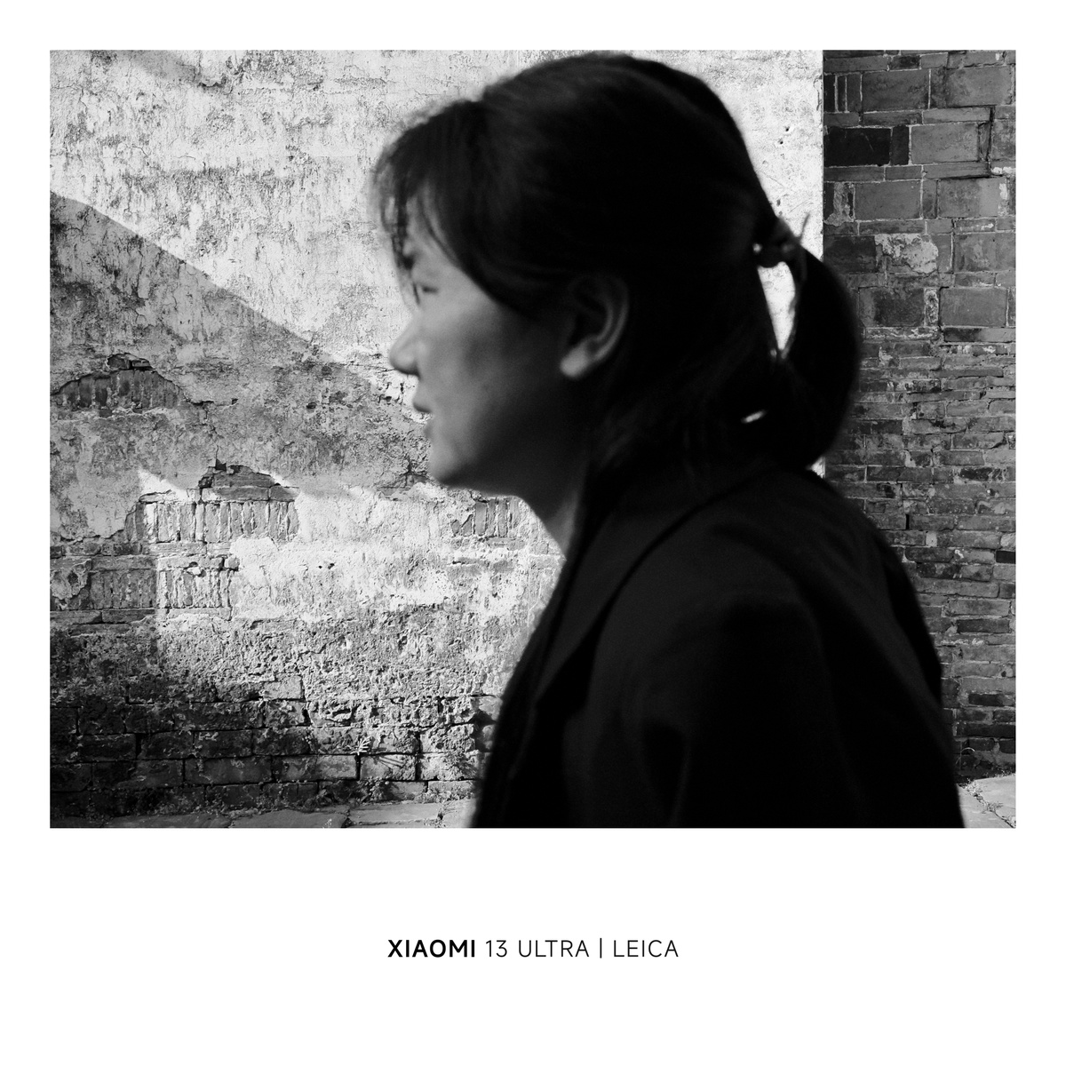 黑白照片 一位年轻女子站在砖墙前