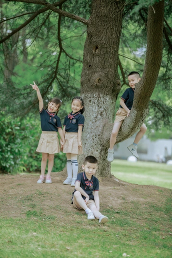 公园里 穿着制服的男孩和女孩站在树下 坐在树下