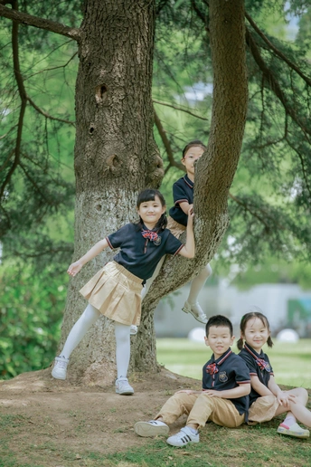 孩子们在公园里摆姿势 一个男孩在爬树 一个女孩坐在树上