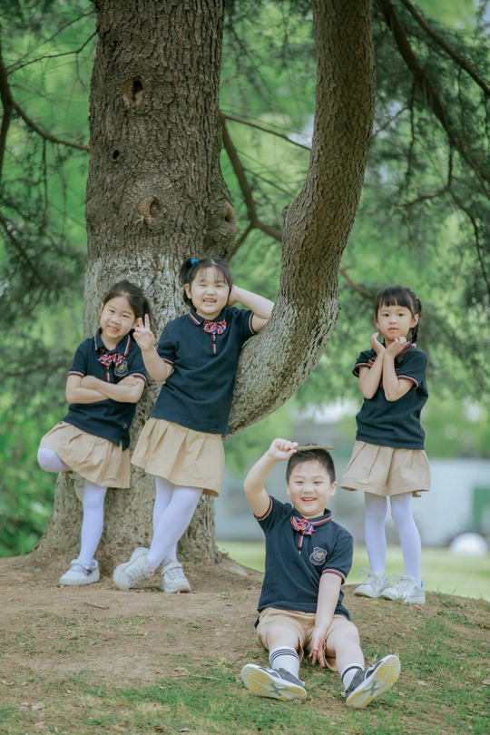 穿着校服的孩子们站在公园的树下