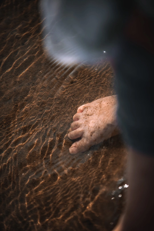 一个人站在浅水处 手和脚在水中