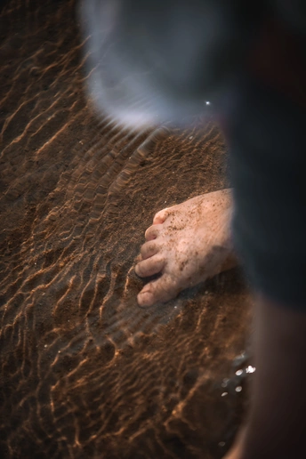 一个人站在浅水处 手和脚在水中