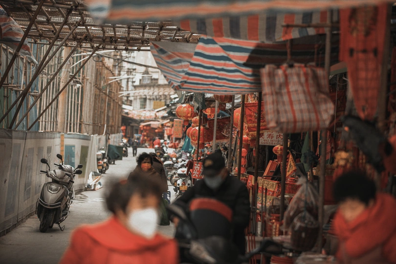 人们戴口罩走在一条狭窄的街道上