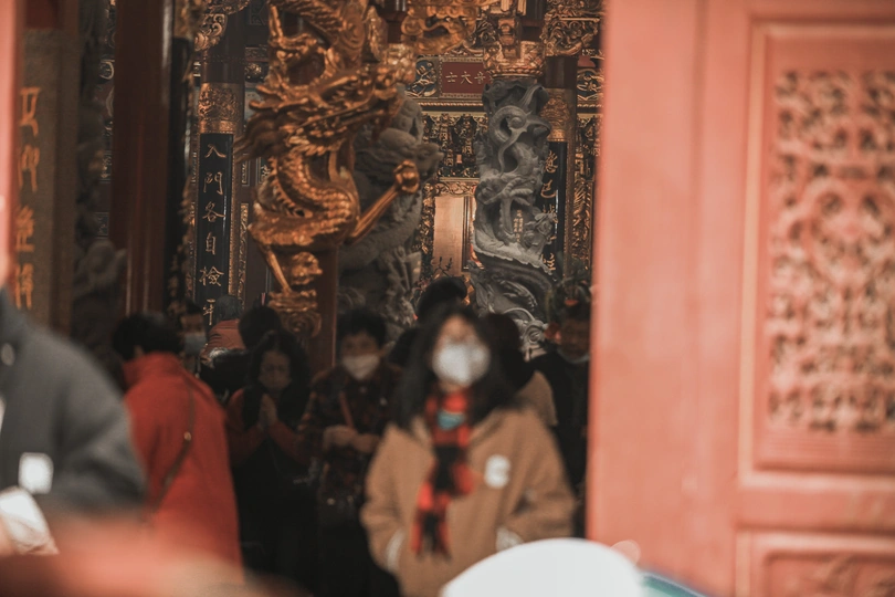 一群戴口罩的人穿过一座寺庙