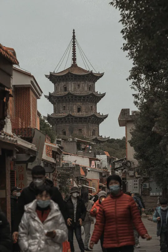 行人戴着防护面罩走在一座古城的街道上