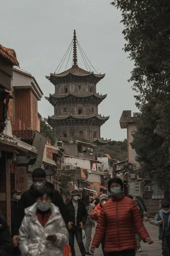 行人戴着防护面罩走在一座古城的街道上