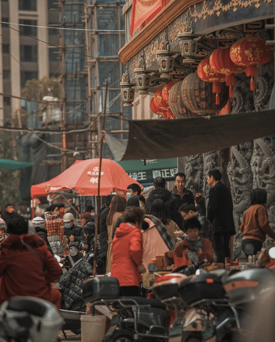 人群沿着街道走 许多摩托车和雨伞。