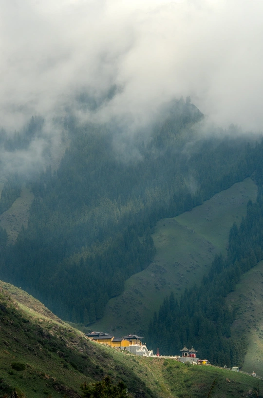 雾和云层笼罩着一个绿色的山谷
