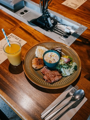 一张木桌 旁边放着一盘食物、一碗沙拉和一杯橙汁