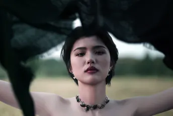 一个穿黑色连衣裙的女人站在一把黑色雨伞下