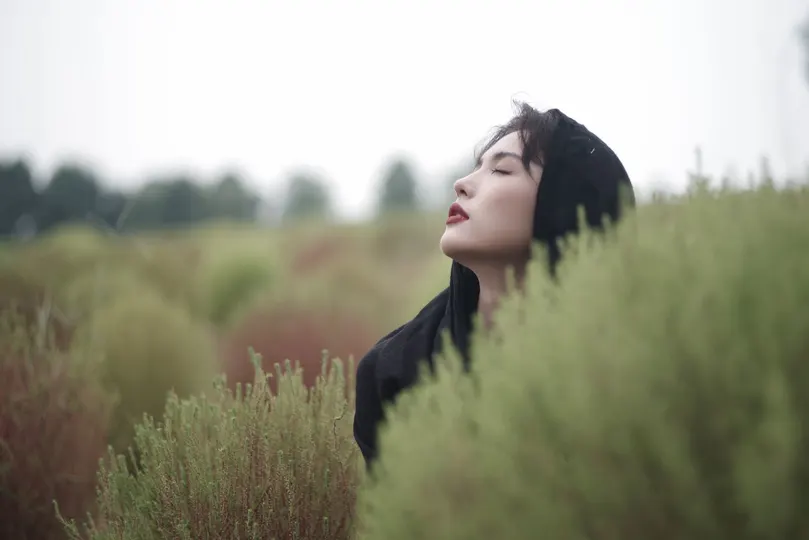 站在一片高草丛中的年轻女子