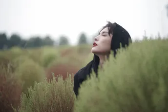 站在一片高草丛中的年轻女子