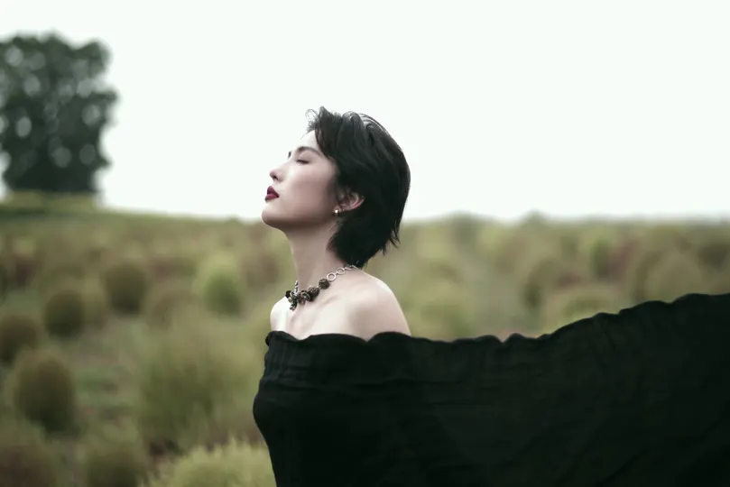 一位穿着黑色连衣裙的女士站在田野中