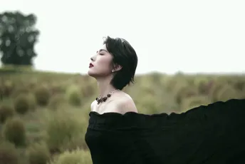 一位穿着黑色连衣裙的女士站在田野中